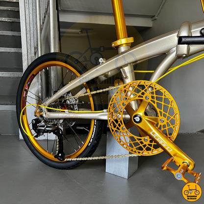 Detailed shot of gold pedals, crankset, and chain on a Crius Velocity 22-inch foldable bike