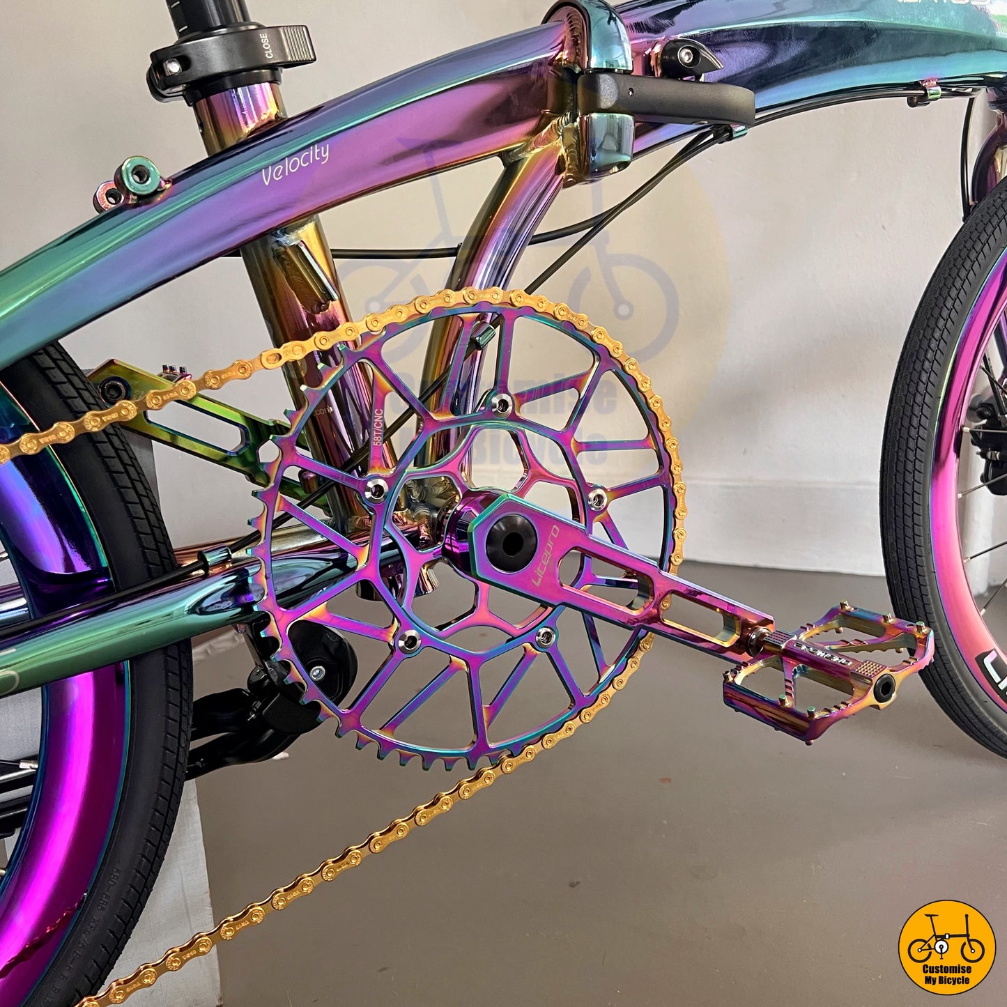 Gold-accented chain and pedals complement the oil slick design
