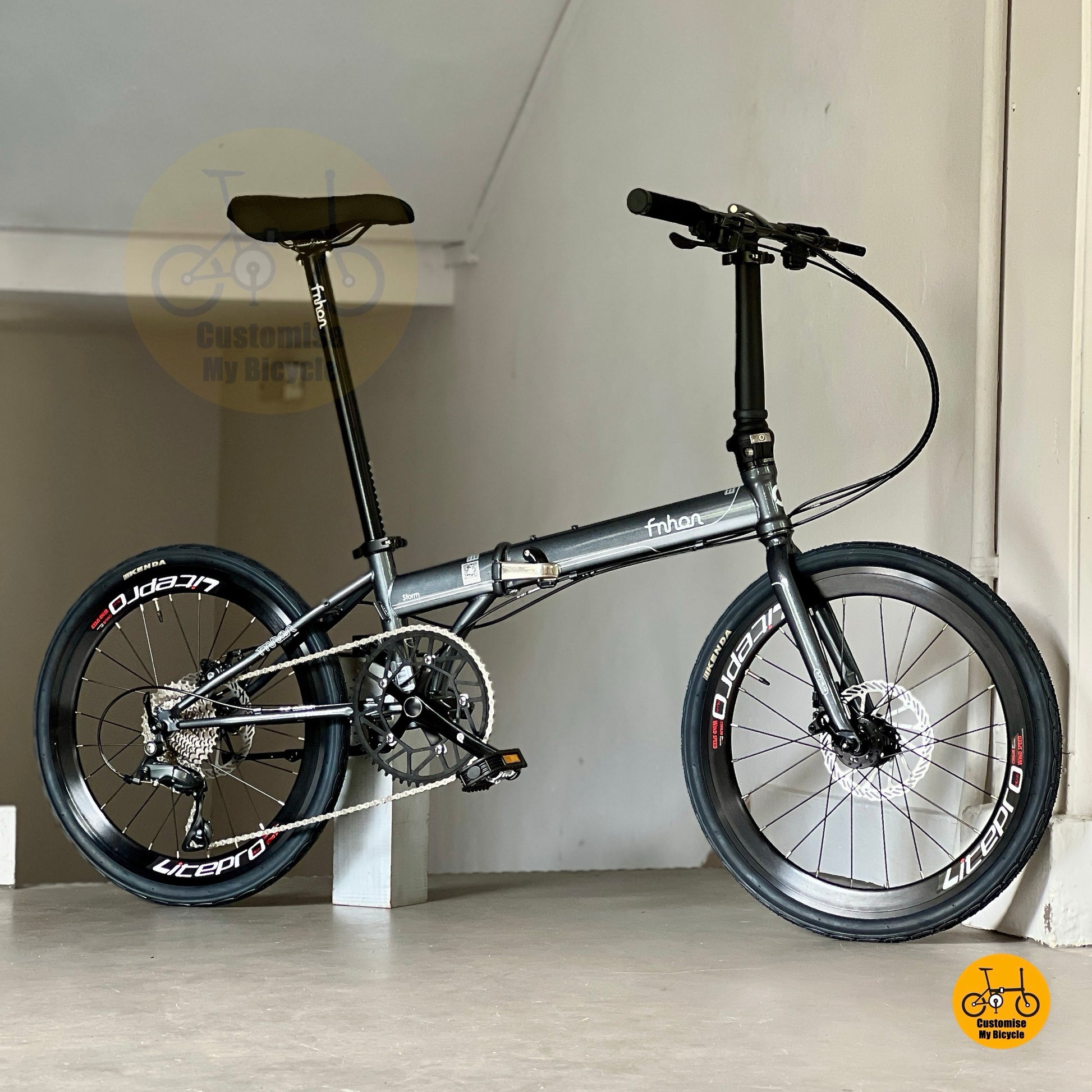Folding bicycle with black frame and wheels on a light colour floor.