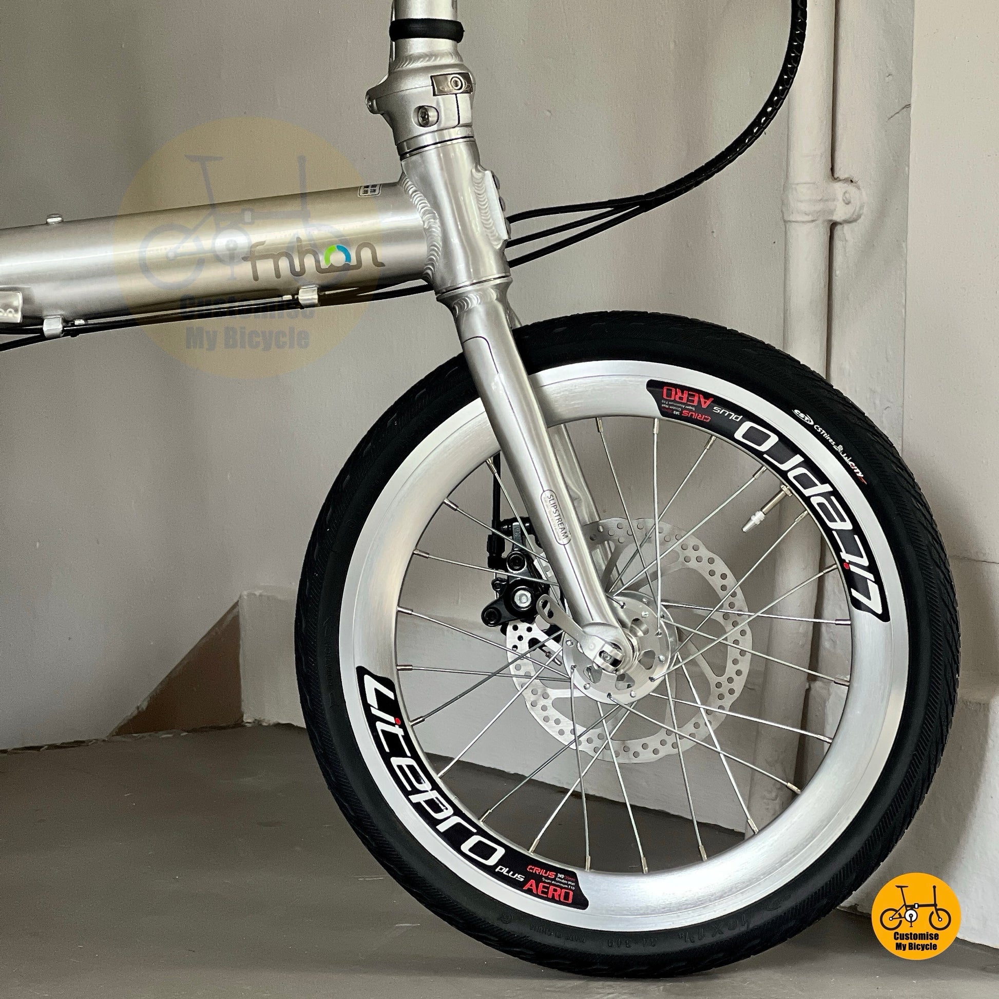 Front wheel and disc brake of Fnhon Zephyr polished silver, featuring Litepro rim and clean spoke design under warm light.
